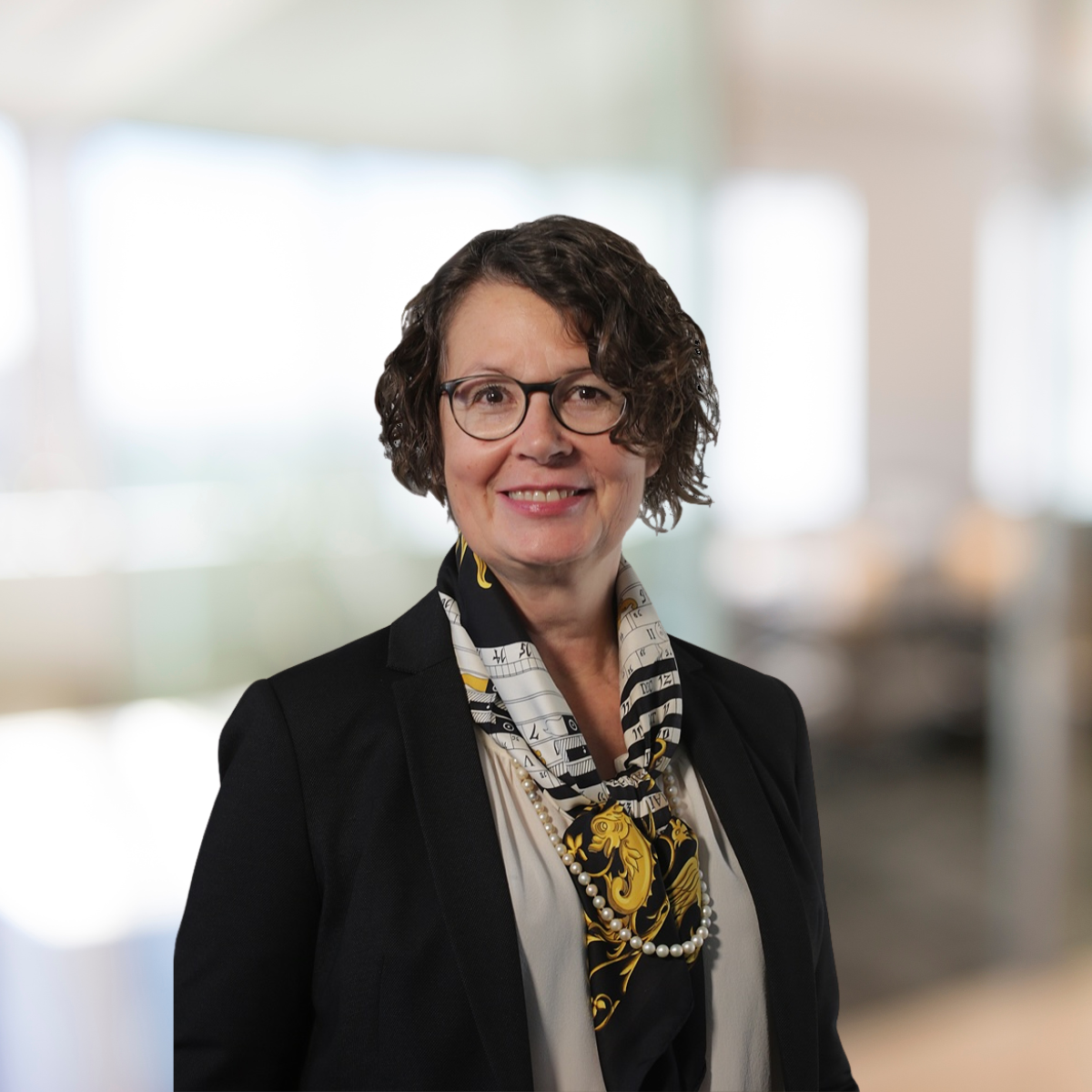 Portraitfoto-Brigitta-Fiesel Auf dem Bild ist Brigitta Fiesel zu sehen. Sie lächelt, trägt eine Brille und einen schwarzen Blazer.