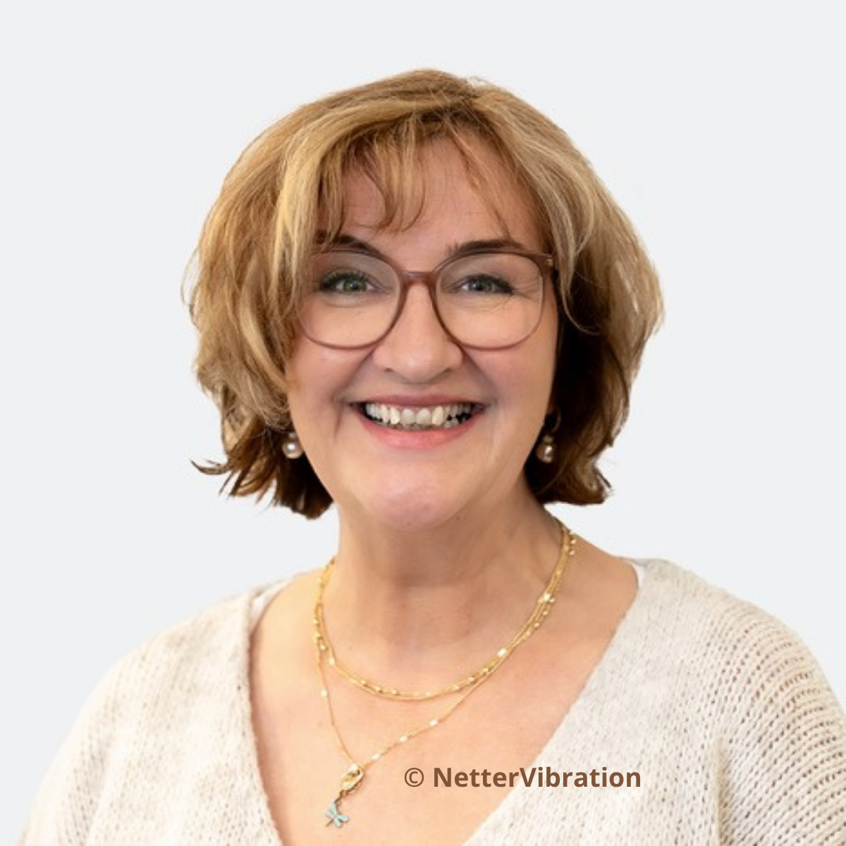 Auf dem Bild ist Claudia Baumer zu sehen. Sie lächelt, trägt eine Brille und cremefarbene Kleidung.